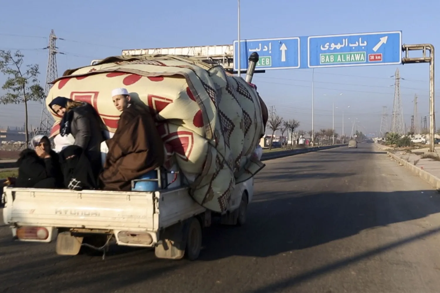 In this frame grab from video taken on Thursday, Dec. 19, 2019, a family with their goods loaded on a lorry drives towards the Turkish border in Syria's Idlib province. (AP)