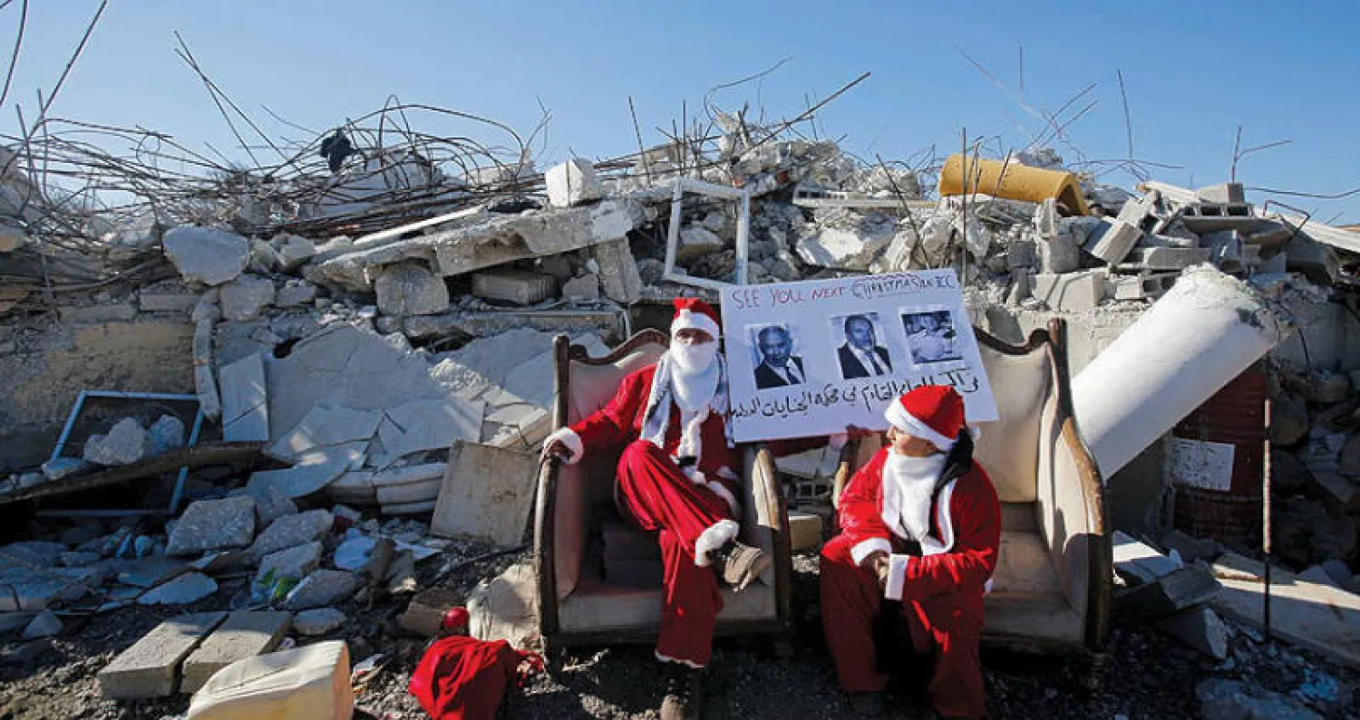 فلسطينيان برداء سانتا كلوز يحتجان على هدم بيوت في الضفة (رويترز)