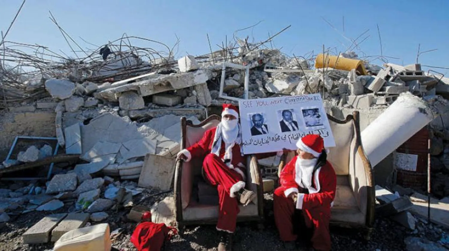Two Palestinians wearing Santa Claus outfit and protesting the demolition of homes in the West Bank (Reuters)