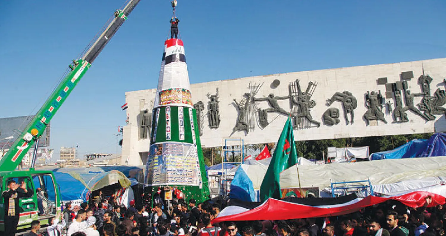 شجرة ميلاد نُصبت في ساحة التحرير وسط بغداد أمس ووضعت عليها صور قتلى من المحتجين (أ.ب)