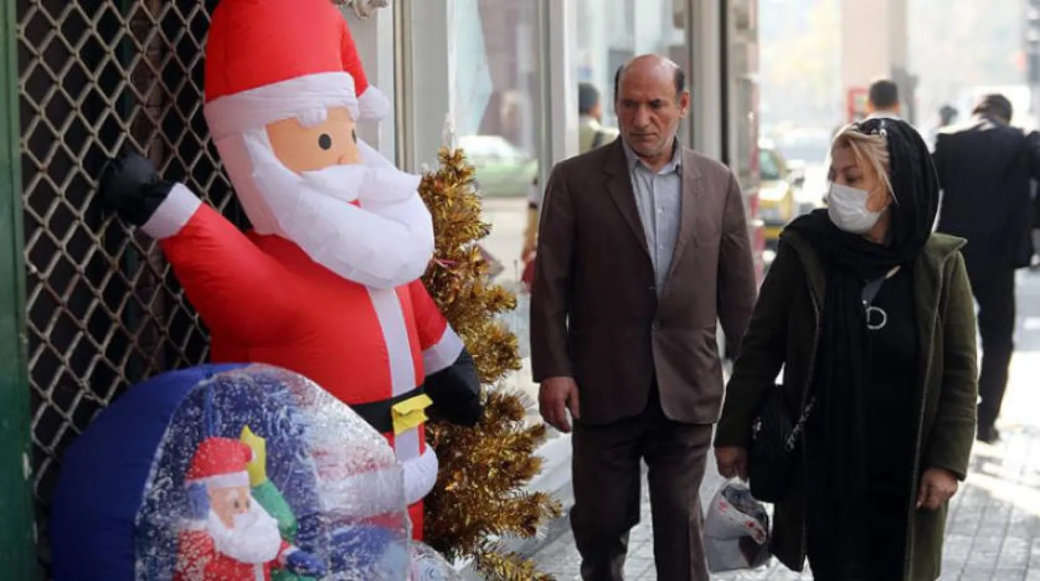 Two Iranians pass in front of a store that sells Christmas items in Tehran on Wednesday, December 25, 2019 (EPA)

