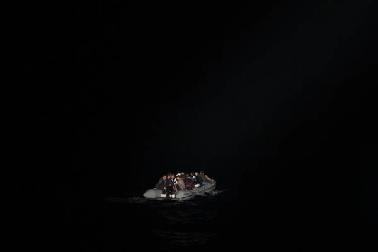 In this early Thursday, Sept. 26, 2019 photo, refugees and migrants in a dinghy are lit by a a Greek coast guard patrol boat's spotlight during a rescue operation near the eastern Aegean Sea island of Samos. AP