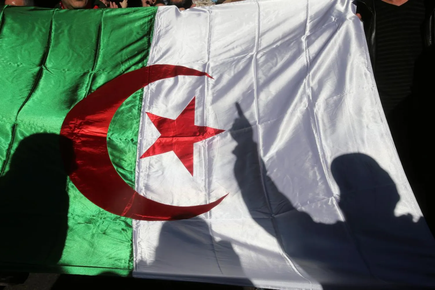 A demonstrator's shadow is cast on a national flag during an anti-government rally in Algiers, Algeria December 24, 2019. (Reuters)