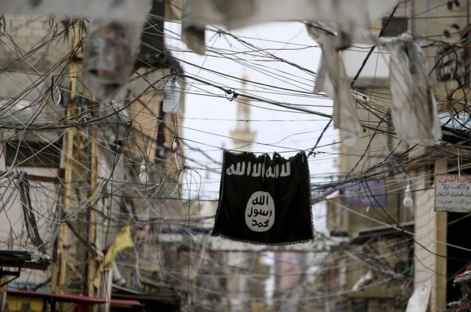 An ISIS flag hangs amid electric wires | REUTERS/Ali Hashisho