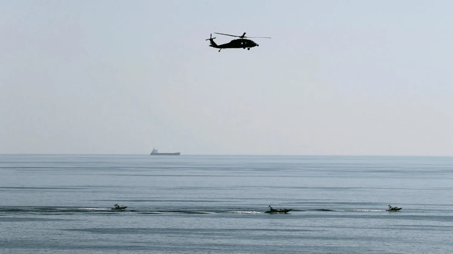 A helicopter hovers over Iranian Revolutionary Guards speed boats seen near the USS John C. Stennis CVN-74 as it makes its way to the Gulf through the Strait of Hormuz. (Reuters)