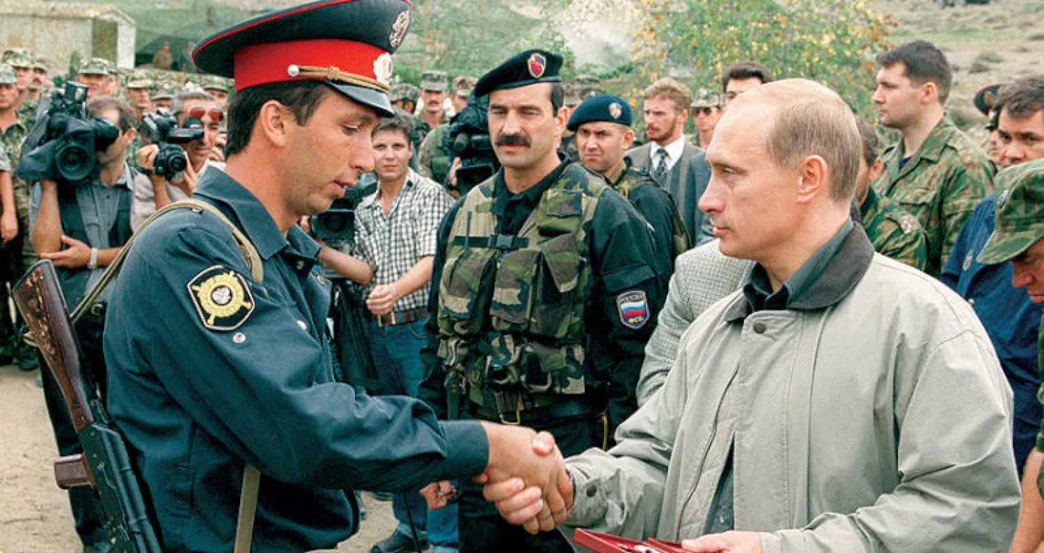 صورة أرشيفية لبوتين وهو يصافح شرطياً في قاعدة عسكرية بداغستان في أغسطس 1999 (أ.ب)