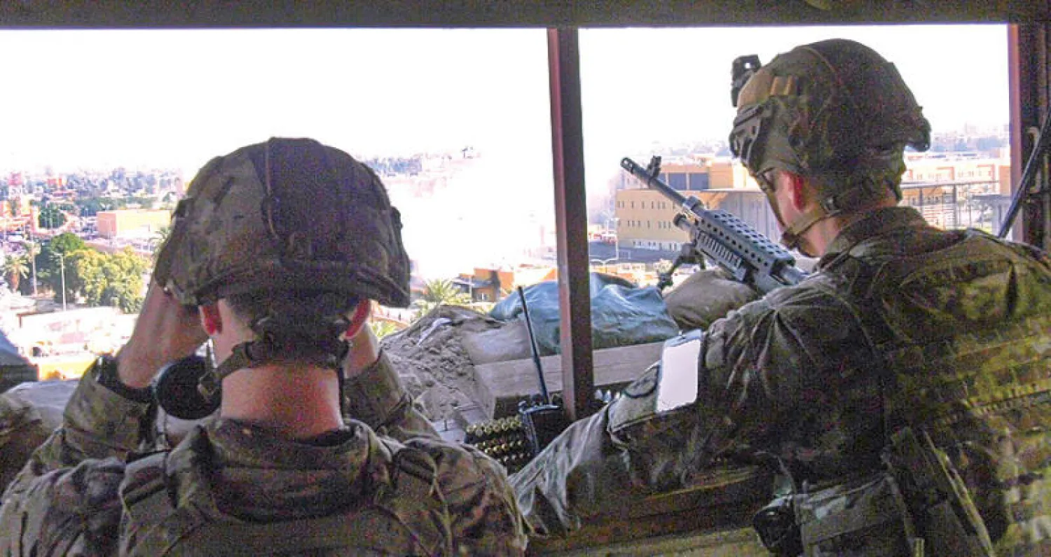 صورة وزعتها سلطات الدفاع الأميركية تظهر جنديين أميركيين يراقبان عن بعد المتظاهرين خارج سفارة الولايات المتحدة في بغداد أمس (إ.ب.أ)