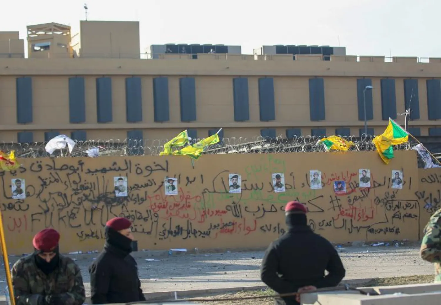 صور لمقاتلين من «كتائب حزب الله» وضعها محتجون على جدار السفارة الأميركية في بغداد (أ.ف.ب)