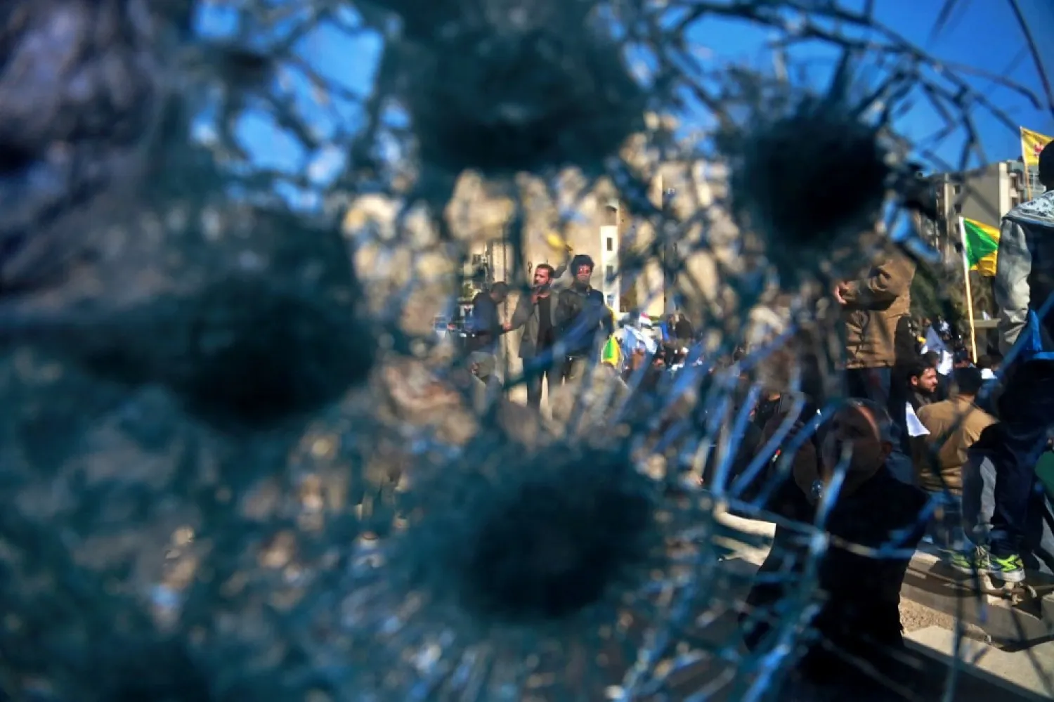 Shiite militia supporters are seen through a broken window of a checkpoint in front of the US embassy, in Baghdad, Iraq, Tuesday, Dec. 31, 2019. (AP)