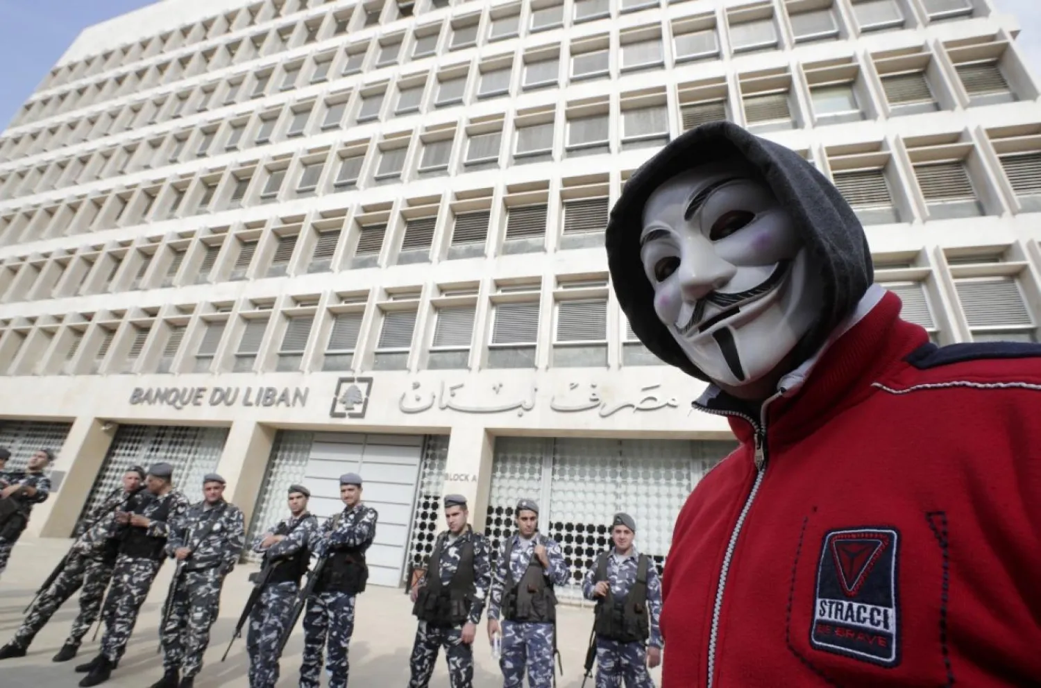 A demonstrator looks on as Lebanese policemen stand guard outside the Central Bank in Beirut last year (AFP)