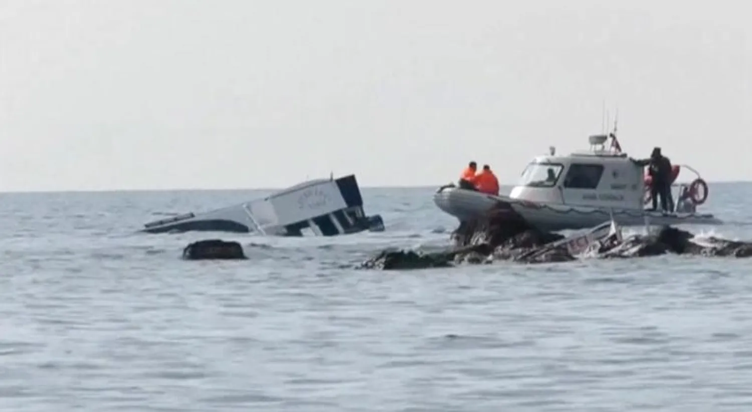 A boat (L) which carried migrants sinks into the sea off Turkey's western coast of Ayvacik, are seen in this still image from video taken January 30, 2016. REUTERS/Reuters TV

