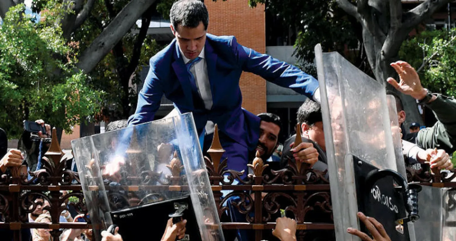 غوايدو يتسلّق سياج البرلمان الفنزويلي بعدما رفضت السلطات السماح له بالدخول أول من أمس (أ.ف.ب)