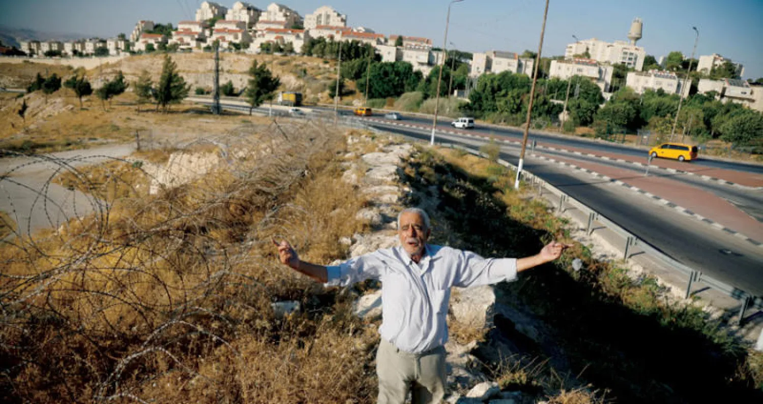 الفلسطيني علي فارون من العيزرية قرب القدس وخلفه مستوطنة يهودية في الضفة (رويترز)
