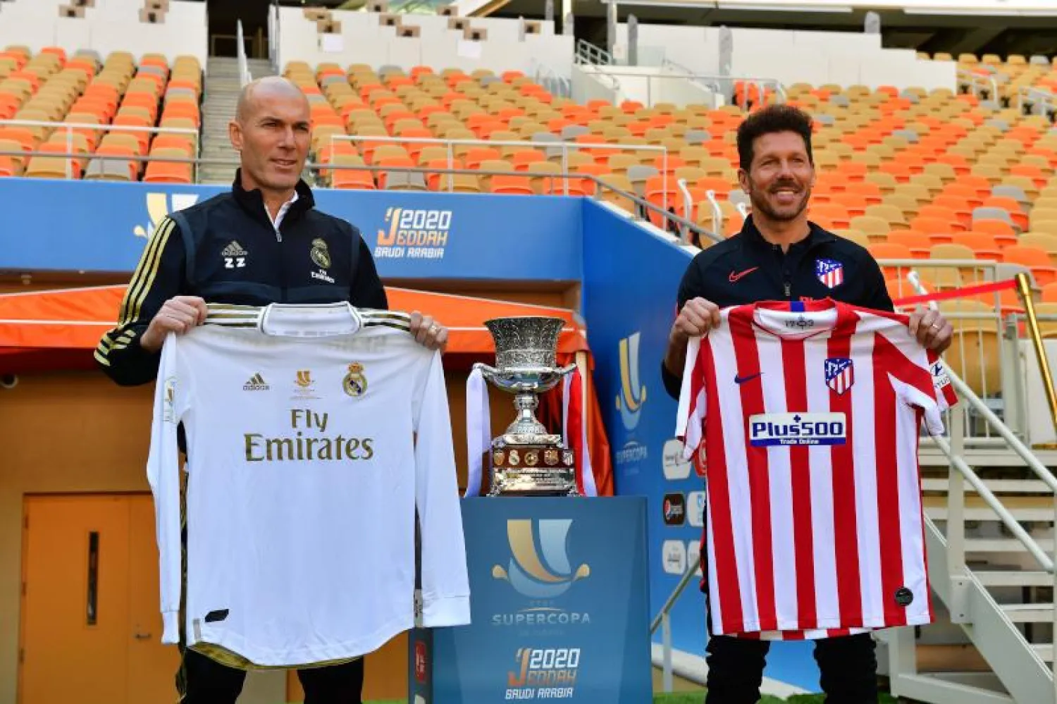 دييغو سيميوني (يمين) وزين الدين زيدان وبينهما كأس السوبر الإسبانية (أ.ف.ب)