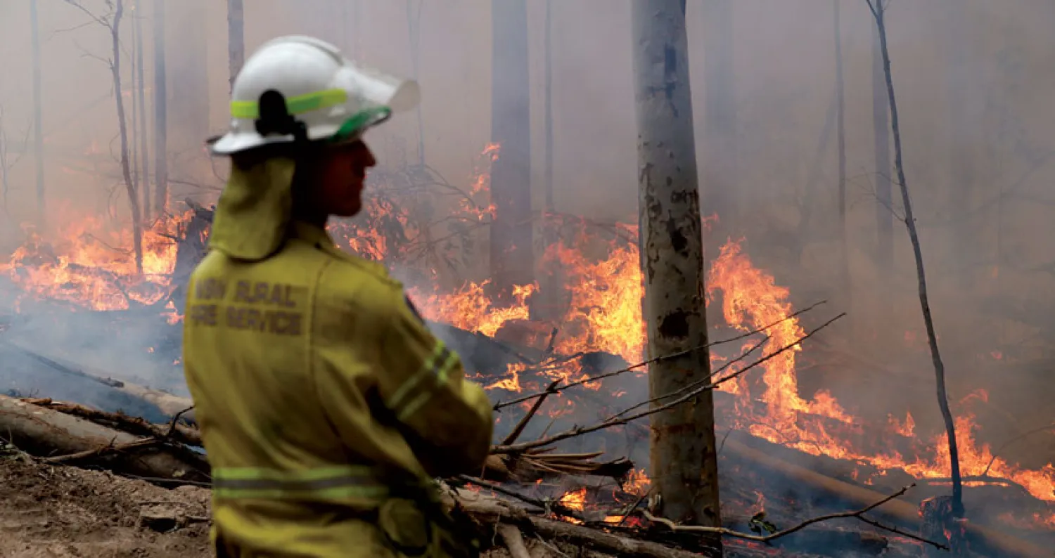 إطفائي يراقب حريقاً متعمداً للحد من انتشار النيران في بودالا أمس (أ.ب)