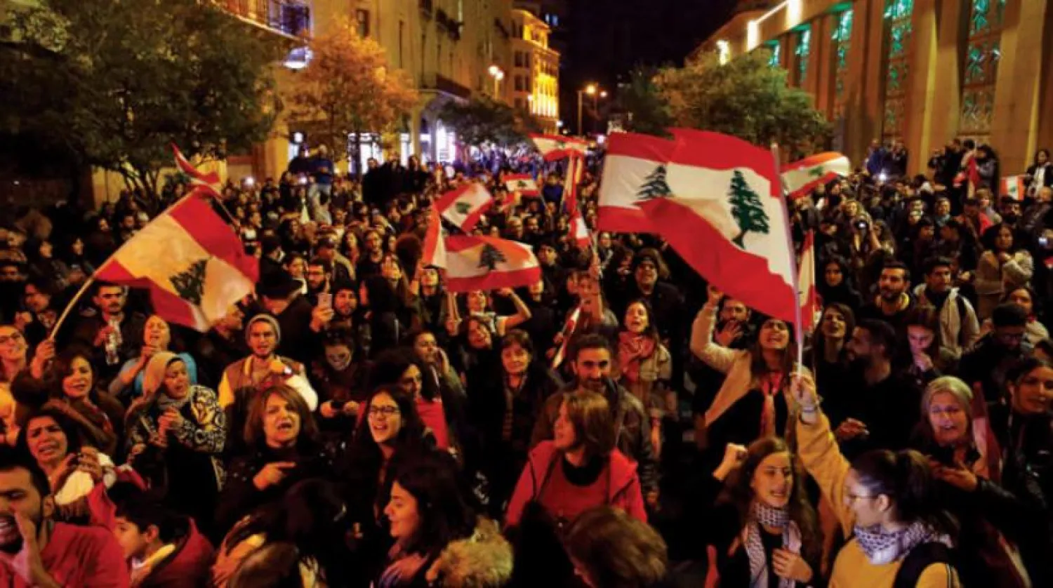 Protesters chant slogans as they hold national flags during ongoing protests against the Lebanese political class, at a road leading to the parliament building in Beirut, Lebanon, Saturday, Jan. 11, 2020. (AP Photo/Bilal Hussein)
