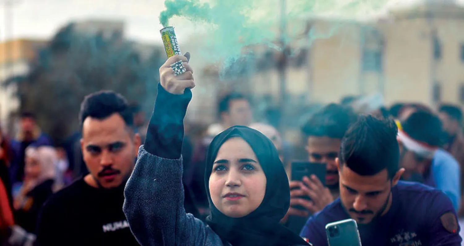 عراقيون خلال احتجاجات على هامش «مهرجان الألوان» خارج جامعة الكوفة في مدينة النجف أمس (أ.ف.ب)