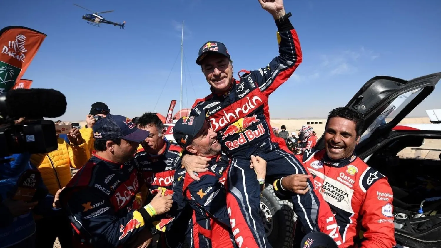 First-placed for the auto category JCW X-RAID Mini Team Spain's driver Carlos Sainz (C), celebrates as he is congratulated by second-placed Toyota's team Qatar's driver Nasser Al-Attiyah (R) and by third-placed JCW X-RAID Mini Team France's Stephane Peterhansel on the finish area in Qiddiya at the end of the stage 12 of the Dakar 2020 between Haradh and Qiddiya, Saudi Arabia, on January 17, 2020. (Photo by FRANCK FIFE / AFP)