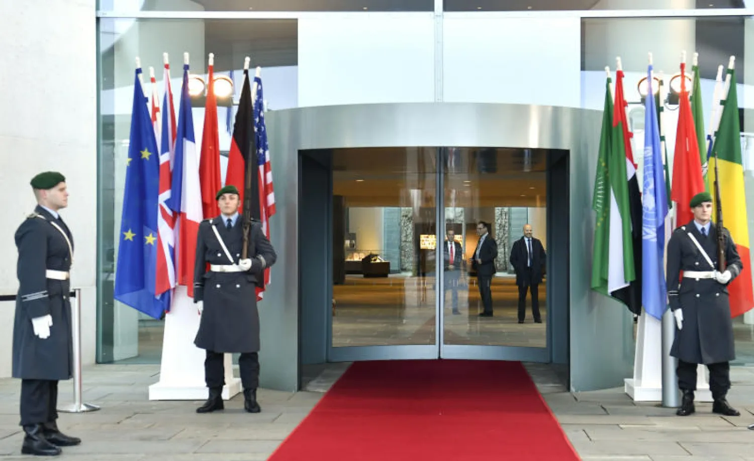 أعلام الدول المشاركة في مؤتمر برلين حول ليبيا أمام مدخل المستشارية الألمانية (أ.ف.ب)