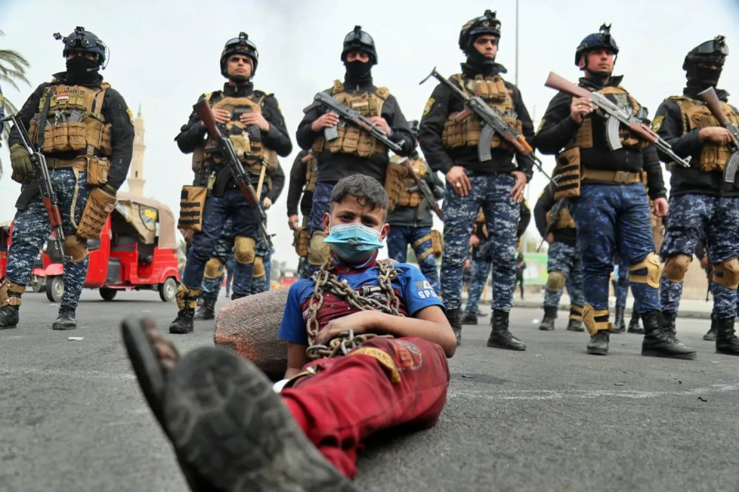 Anti-government protesters stage a sit-in while security forces stand guard during ongoing protests in downtown Baghdad, Iraq, Sunday, Jan. 19, 2020. (AP)
