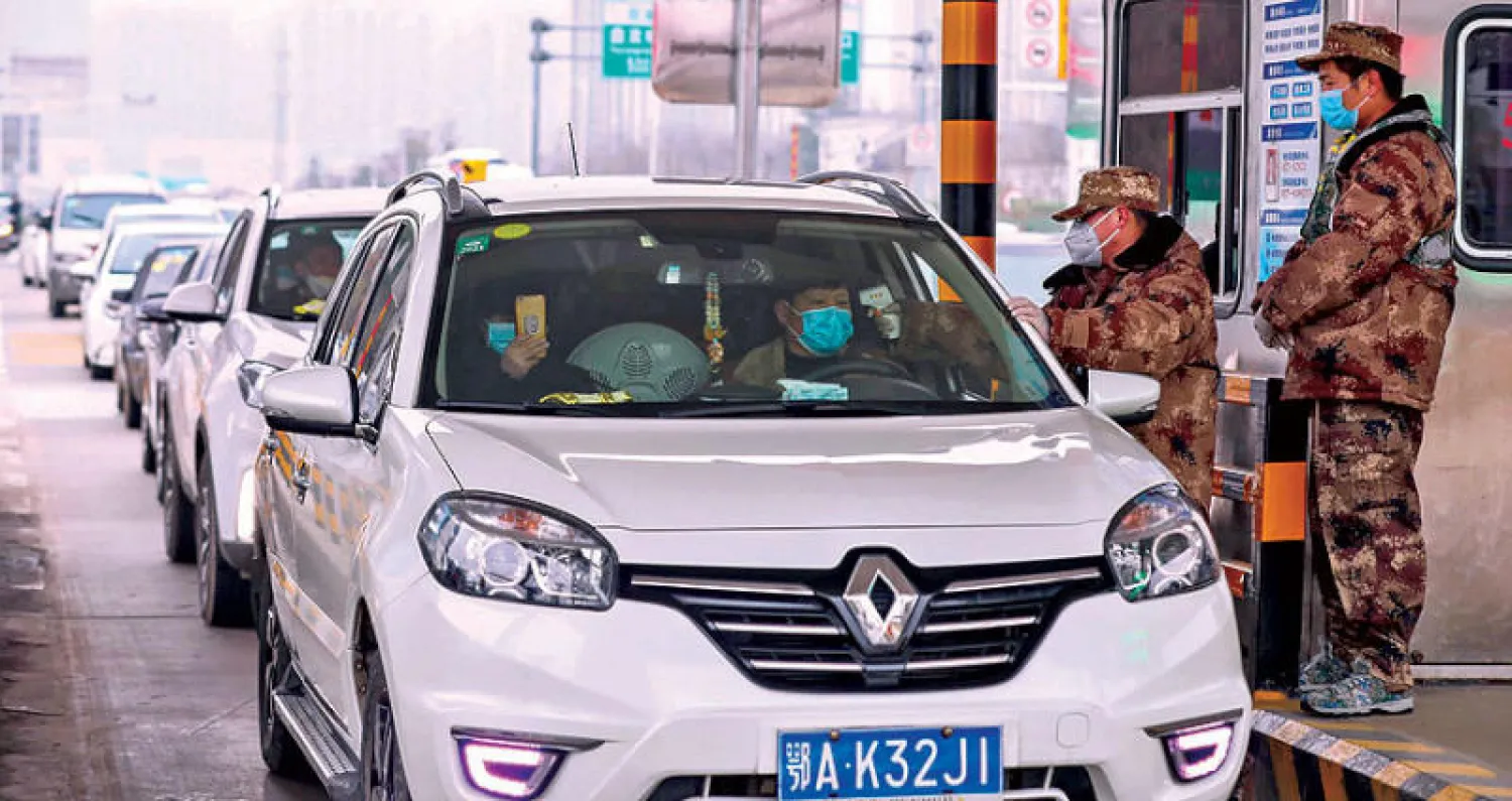 عسكري يفحص أمس درجة حرارة مسافر في مدينة ووهان الصينية التي جرى حجرها صحيا بسبب تفشي فيروس «كورونا»  (إ.ب.أ)