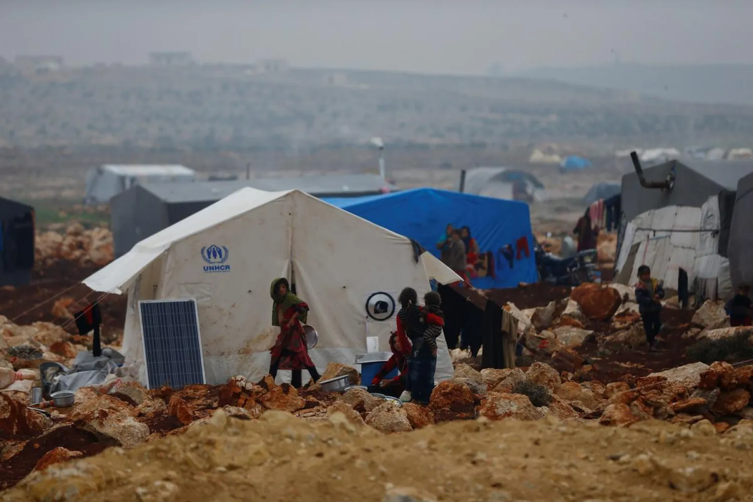 Displaced Syrians stand outside of their tents at Kelbit refugee camp, near the Syrian-Turkish border, in Idlib province, Syria January 17, 2018. REUTERS/Osman Orsal