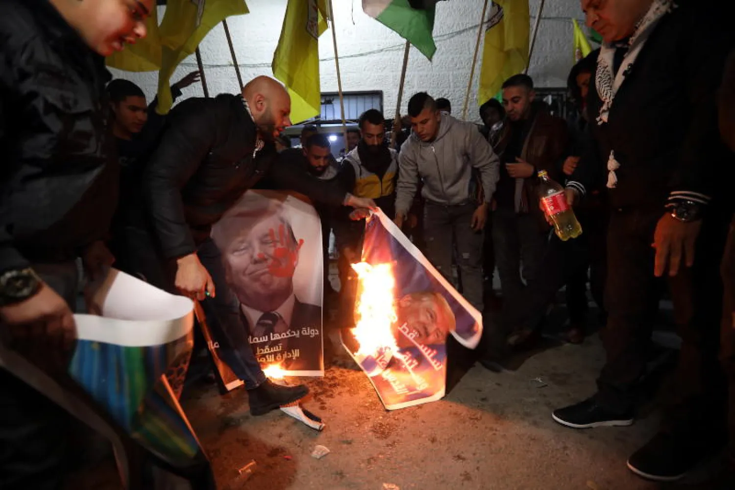 فلسطينيون يحرقون صور ترمب خلال احتجاجات اليوم (إ.ب.أ)