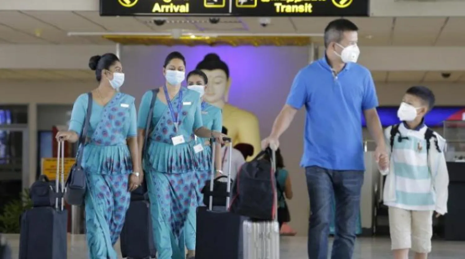 مسافرون سريلانكيون يضعون أقنعة واقية في مطار كولومبو (إ.ب.أ)