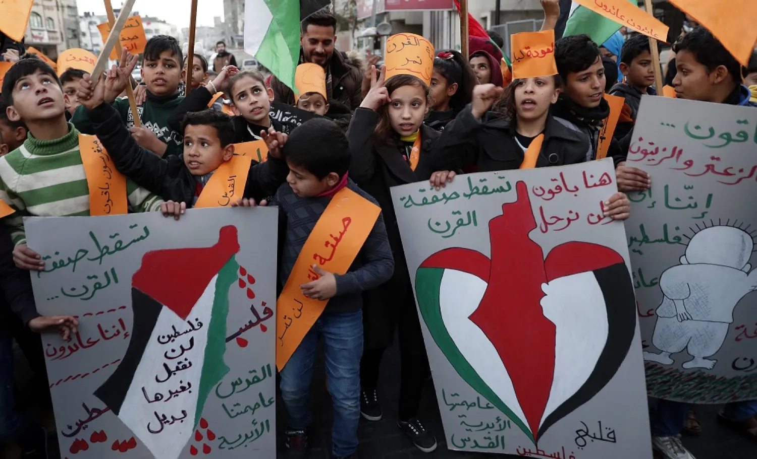 Protesters hold placards as others wave their national flags during a protest against Trump’s Middle East plan, at Jebaliya refugee camp, Gaza Strip, Jan. 30, 2020. (AP)