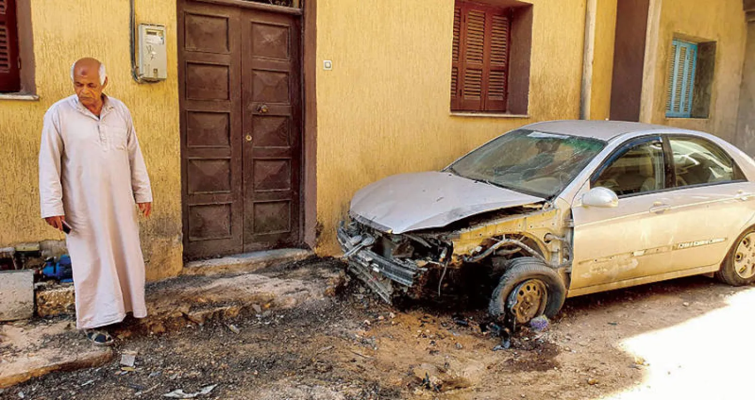 أحد سكان طرابلس يعاين سيارته التي تعرضت للقصف في معارك جنوب العاصمة طرابلس (أ.ف.ب)