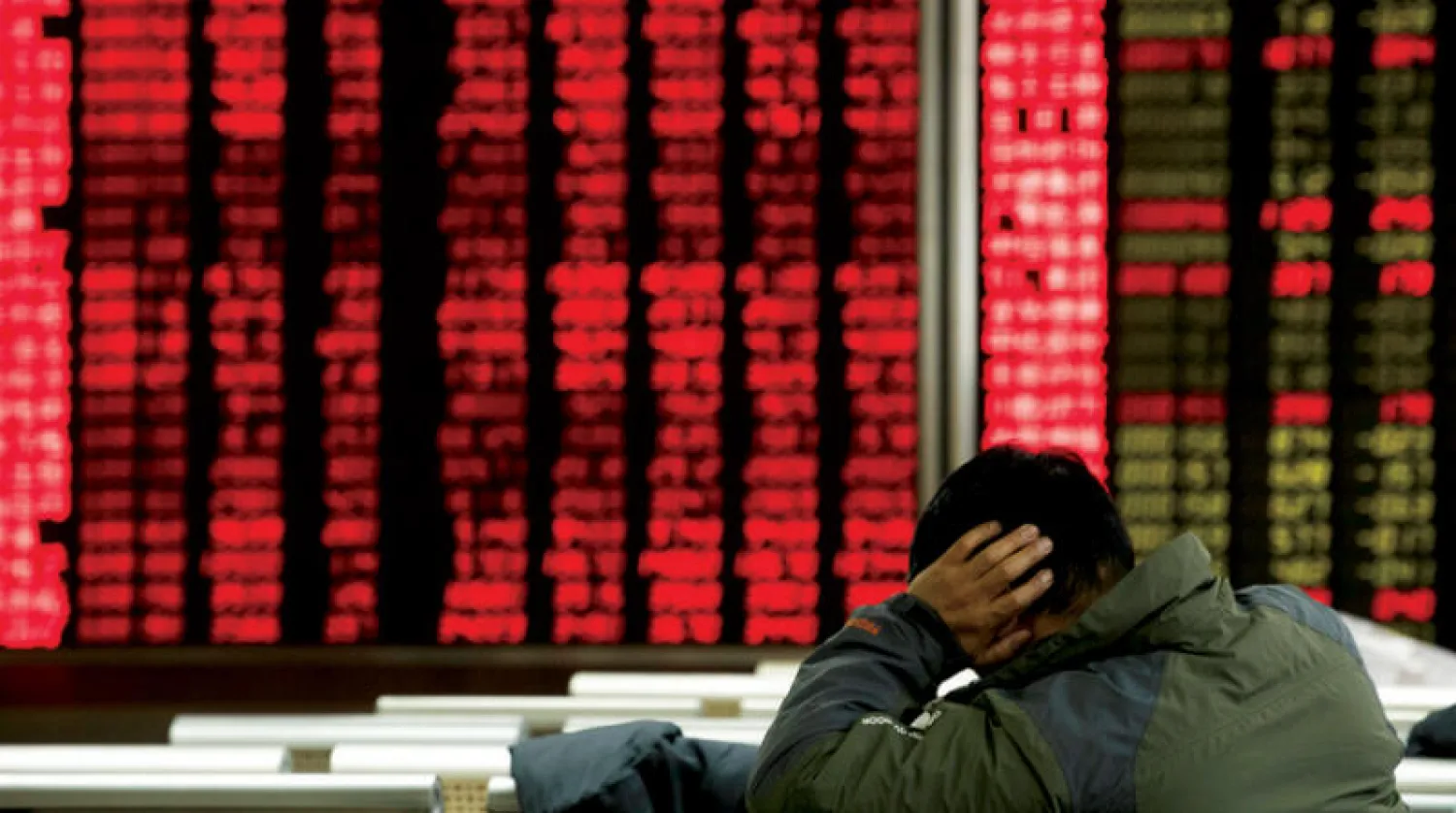 مستثمر يراقب أسعار الأسهم الصينية بشركة وساطة في بكين (أ.ب)