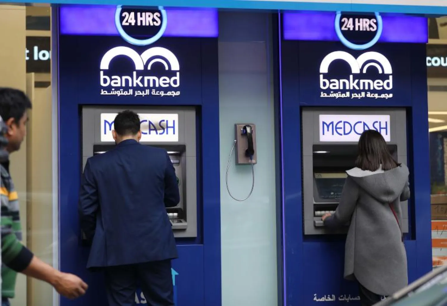 لبنانيون يسحبون أموالاً من ماكينات صراف آلي في العاصمة بيروت (أ.ف.ب)
