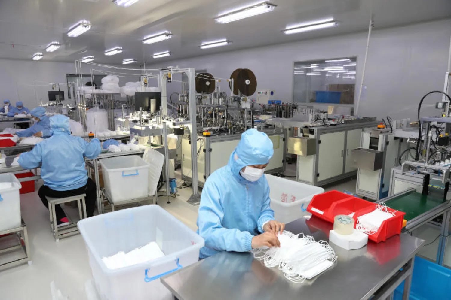 موظفون صينيون يعملون في ورشة لمؤسسة معنية بتصدير المنسوجات لإنتاج 200000 قناع يومياً للمساعدة في الوقاية من فيروس «كورونا» (د.ب.أ)