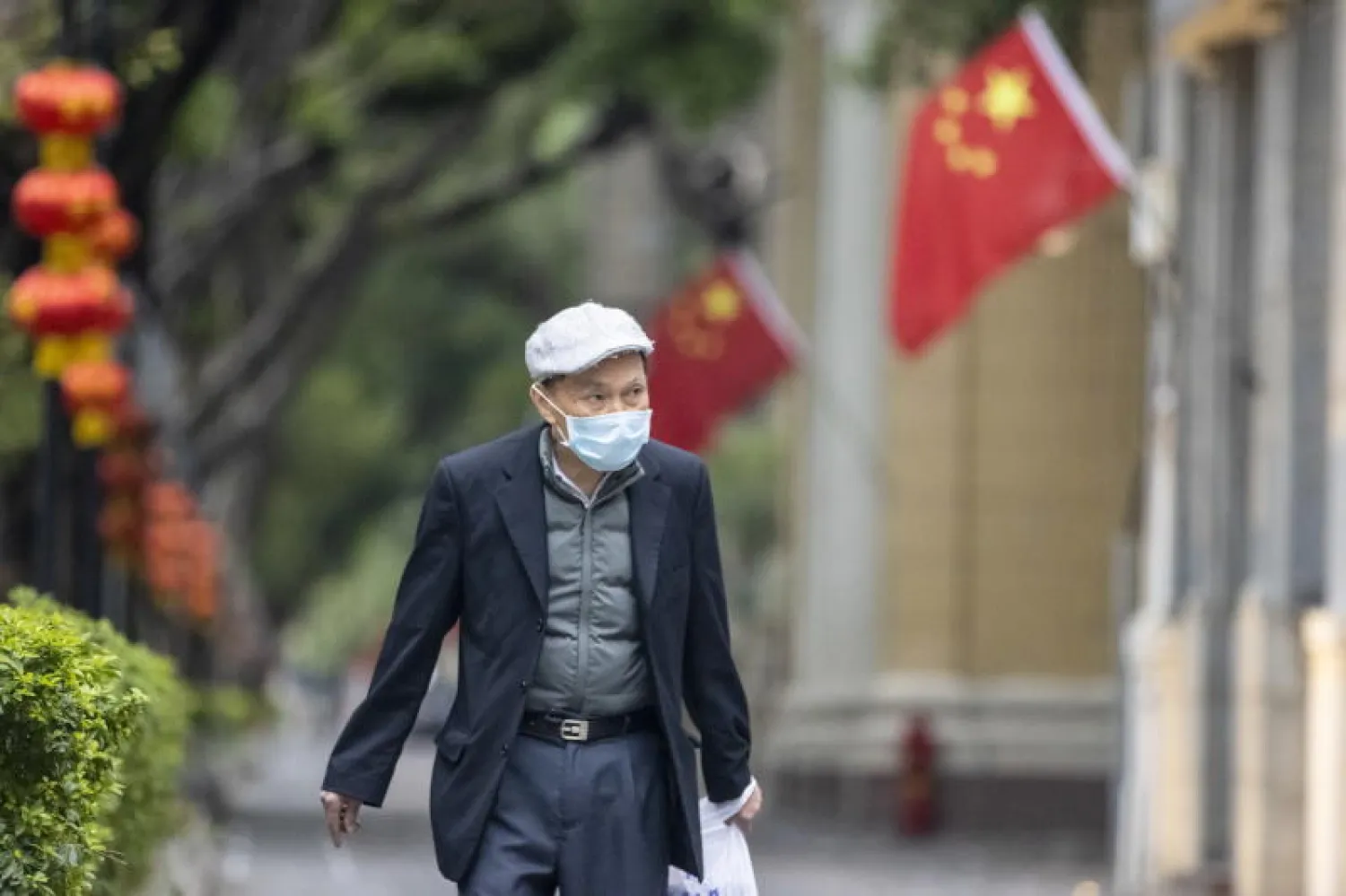 رجل يمشي في الشارع مرتدياً قناعاً وقائياً بمقاطعة غوانغدونغ بالصين (إ.ب.أ)