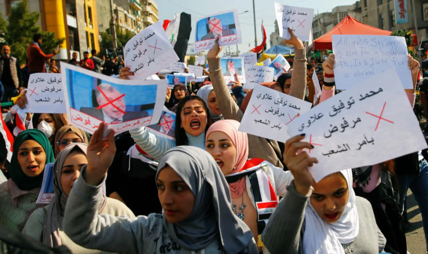 طلاب جامعيون يحملون لافتات رافضة لتكليف محمد علاوي رئاسة الوزراء خلال احتجاجات في بغداد (رويترز)