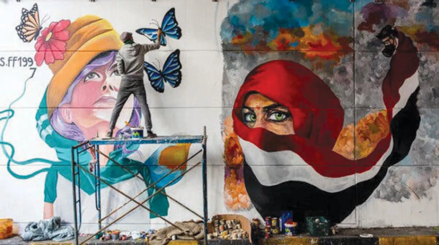 رسم أحد المتظاهرين المناهضين للحكومة لوحة جدارية في شارع السعدون وسط بغداد (نيويورك تايمز)