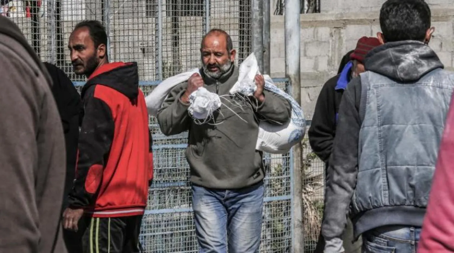 Bir Filistinli, BM Yakın Doğu'daki Filistinli Mültecilere Yardım ve Bayındırlık Ajansı (UNRWA) tarafından Gazze Şeridi’nde dağıtılan gıda yardımı çantalarını taşıyor (AFP)