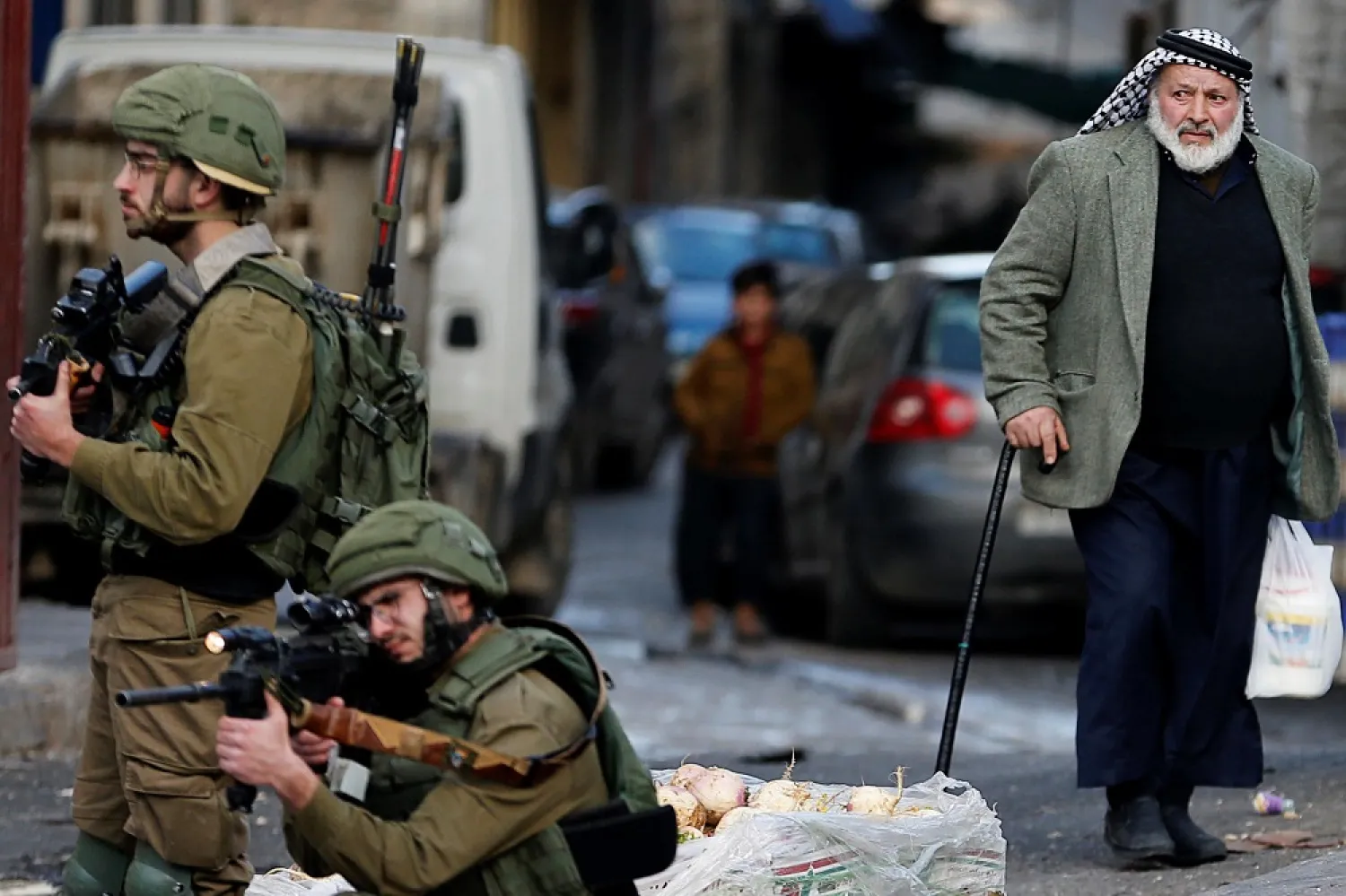 A Palestinian man looks on as an Israeli aims a weapon during a protest against Trump’s Middle East peace plan in Hebron in the Israeli-occupied West Bank on February 6, 2020. (Reuters)