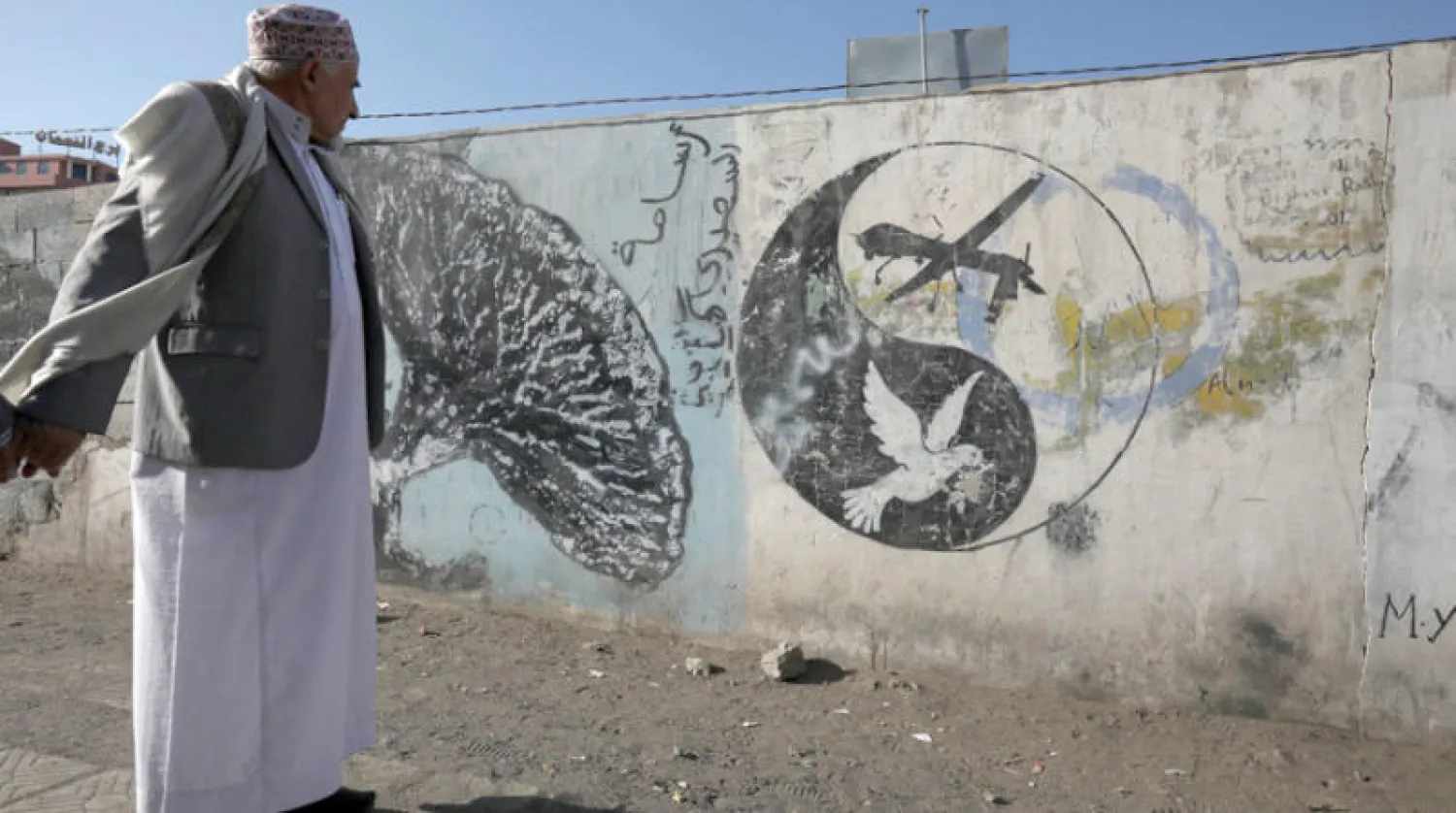 يمني يسير بجوار رسم غرافيتي يصور طائرة أميركية دون طيار (درون) في صنعاء (إ.ب.أ)