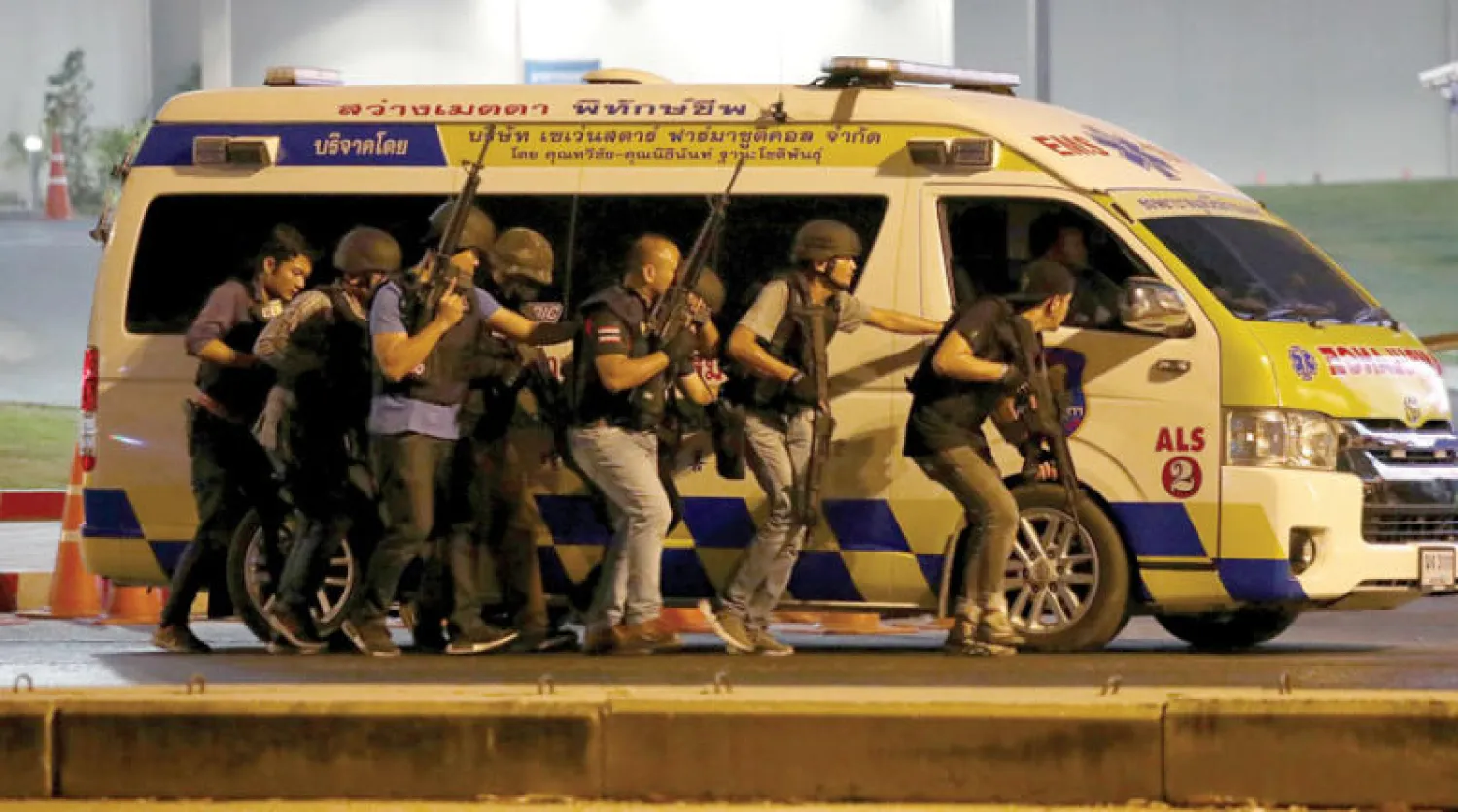 رجال أمن يحتمون بسيارة إسعاف خلال ملاحقة مطلق النار في مدينة كورات أمس (رويترز)