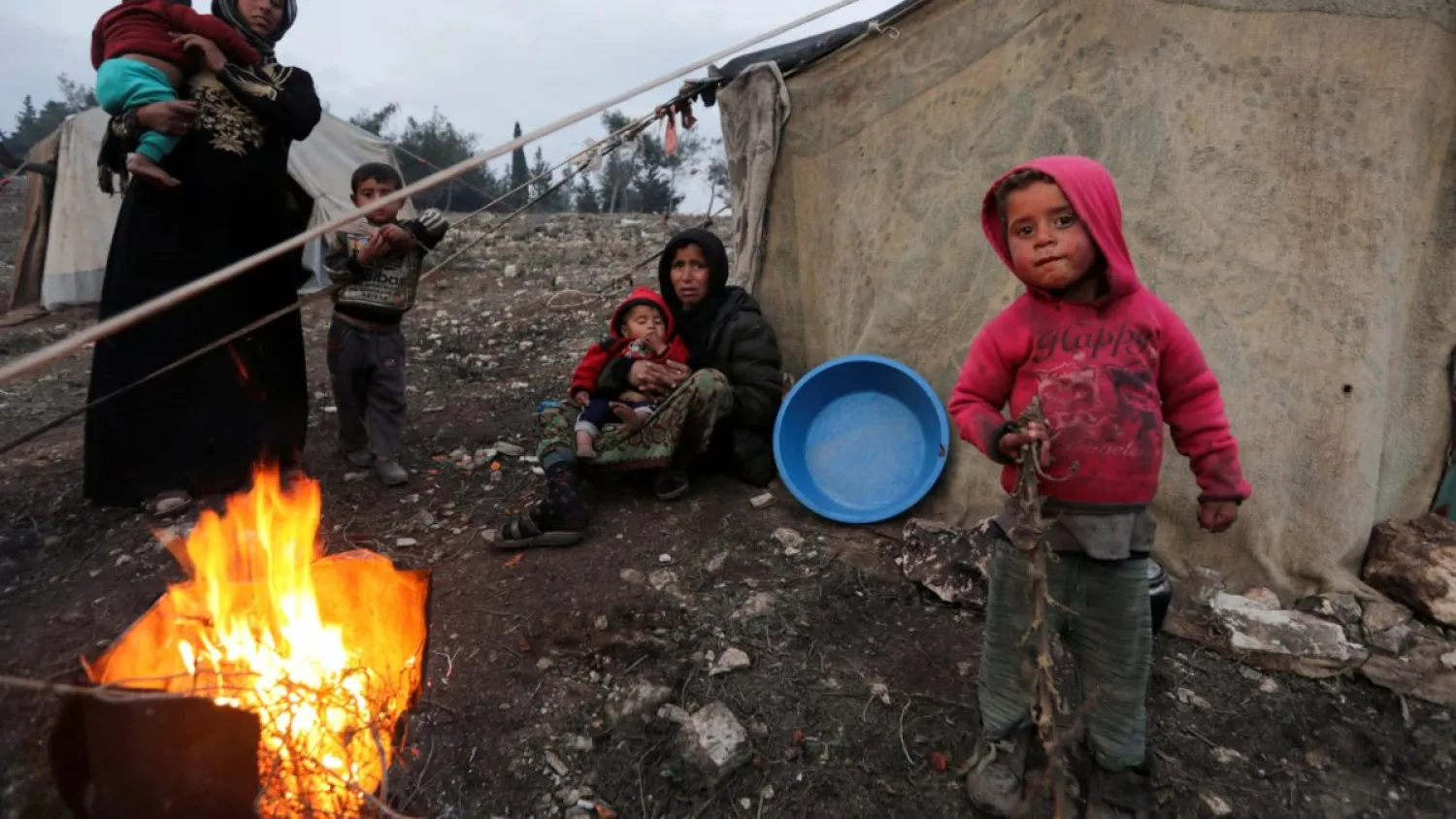 Displaced Syrian women and children, who fled from southern Idlib, gather around a fire in Afrin, Syria, Feb. 6, 2020 | REUTERS