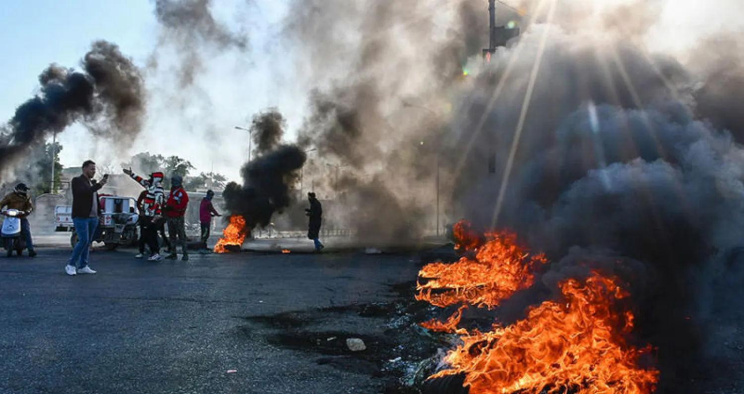 محتجون يغلقون طريقاً بحرق إطارات في الناصرية جنوب العراق أمس (أ.ف.ب)