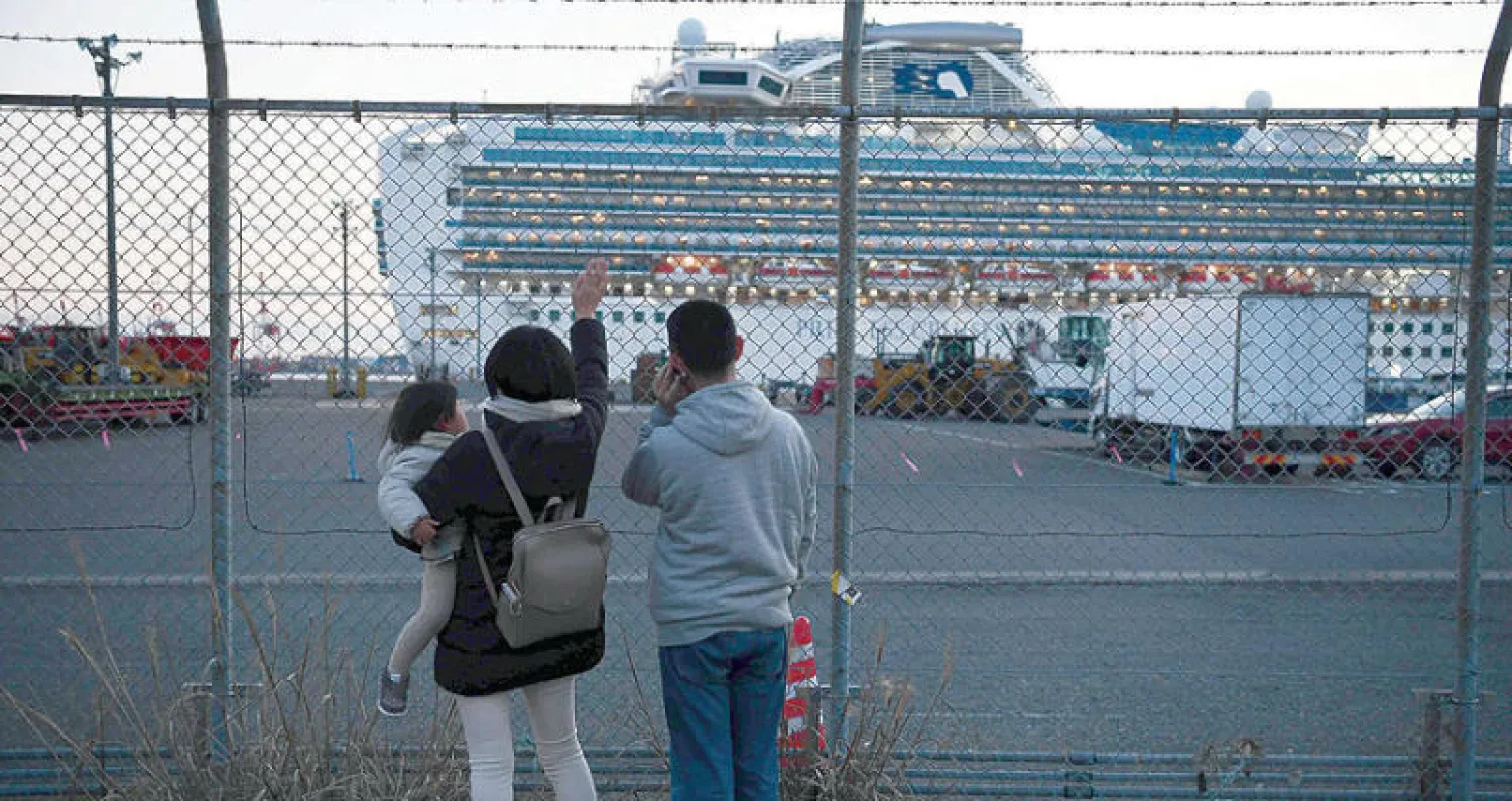 أقارب ركاب عالقين في سفينة سياحية يحيّونهم عن بعد في يوكوهاما أمس (أ.ف.ب)