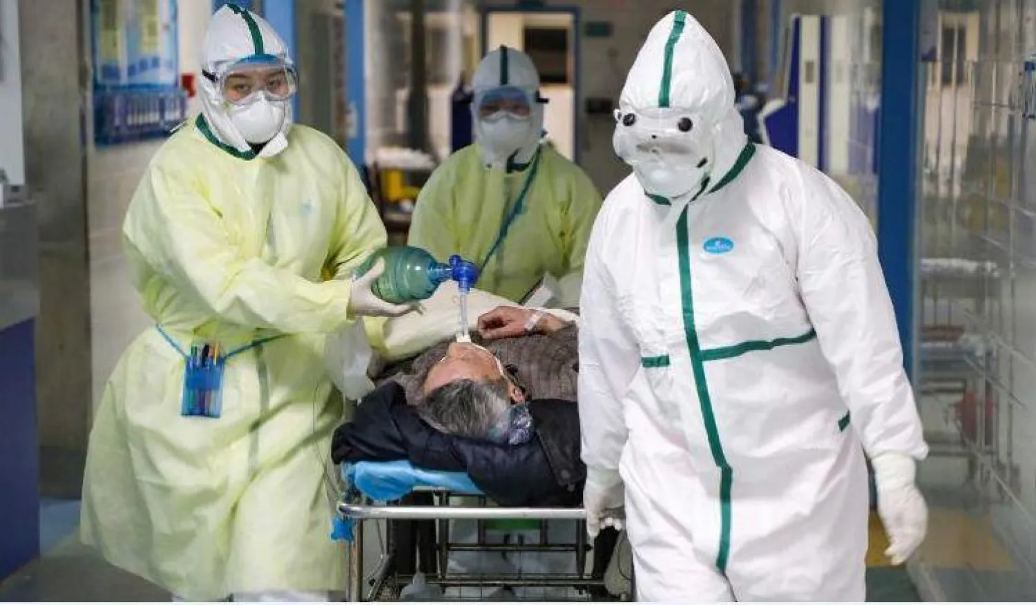 أطباء ينقلون مريضا إلى غرفته بأحد مستشفيات ووهان (رويترز)