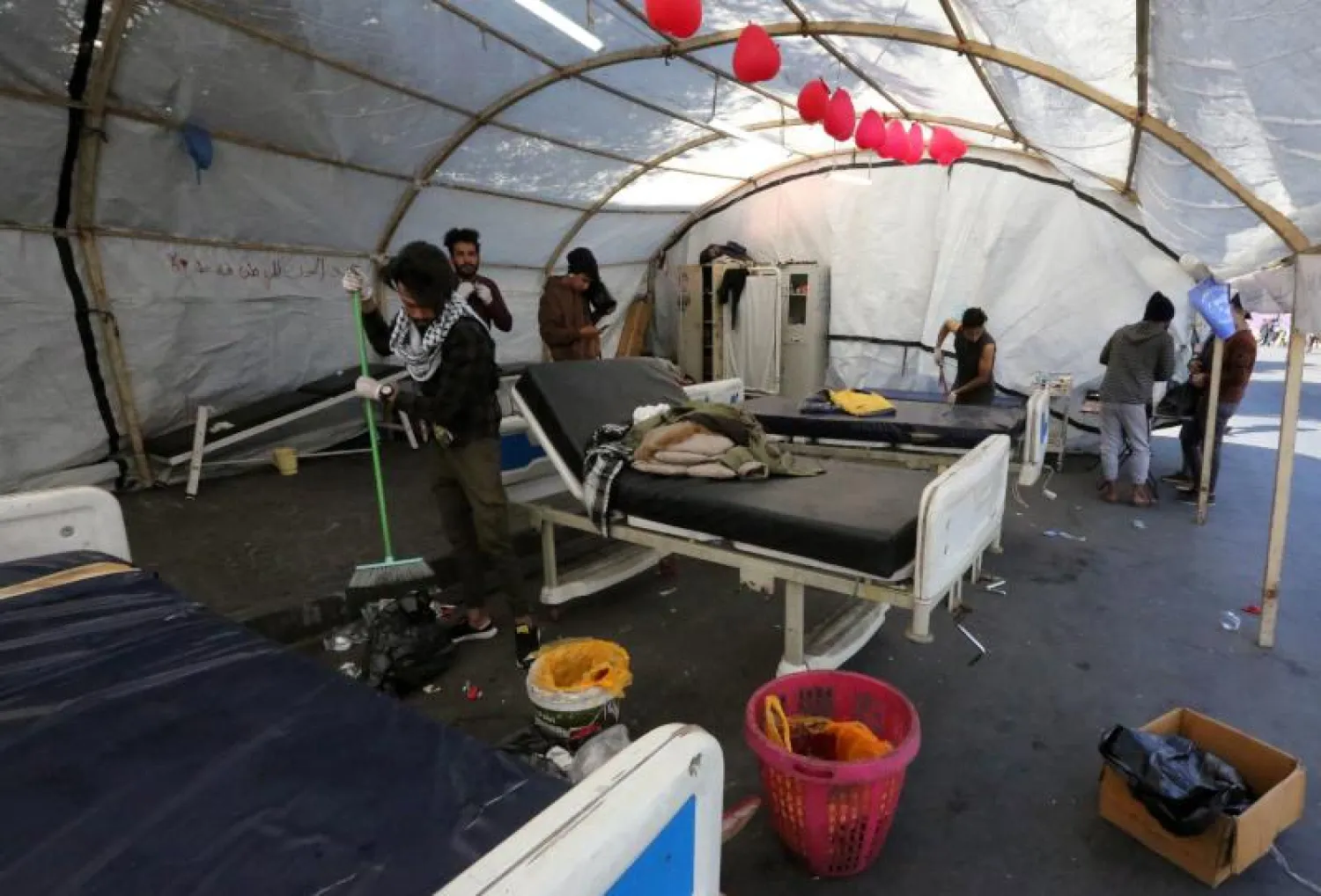 متطوعون ينظفون خيمة تُستخدم كعيادة مؤقتة لعلاج المتظاهرين المصابين في ميدان التحرير ببغداد (أ.ف.ب)