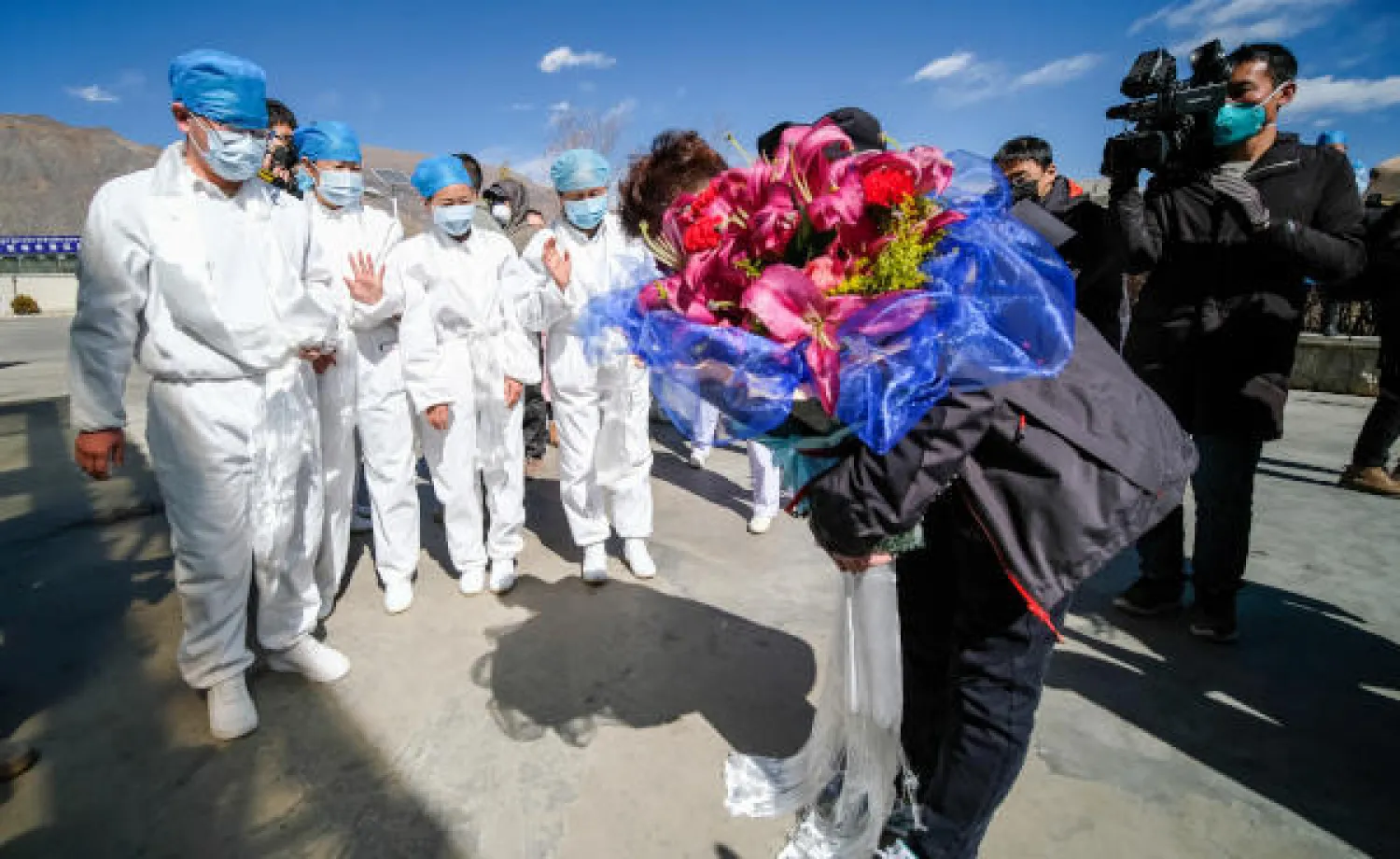 صيني يتلقى باقة ورد أثناء خروجه من المستشفى في لاسا  بعد تعافيه من فيروس كورونا الجديد (د.ب.أ)