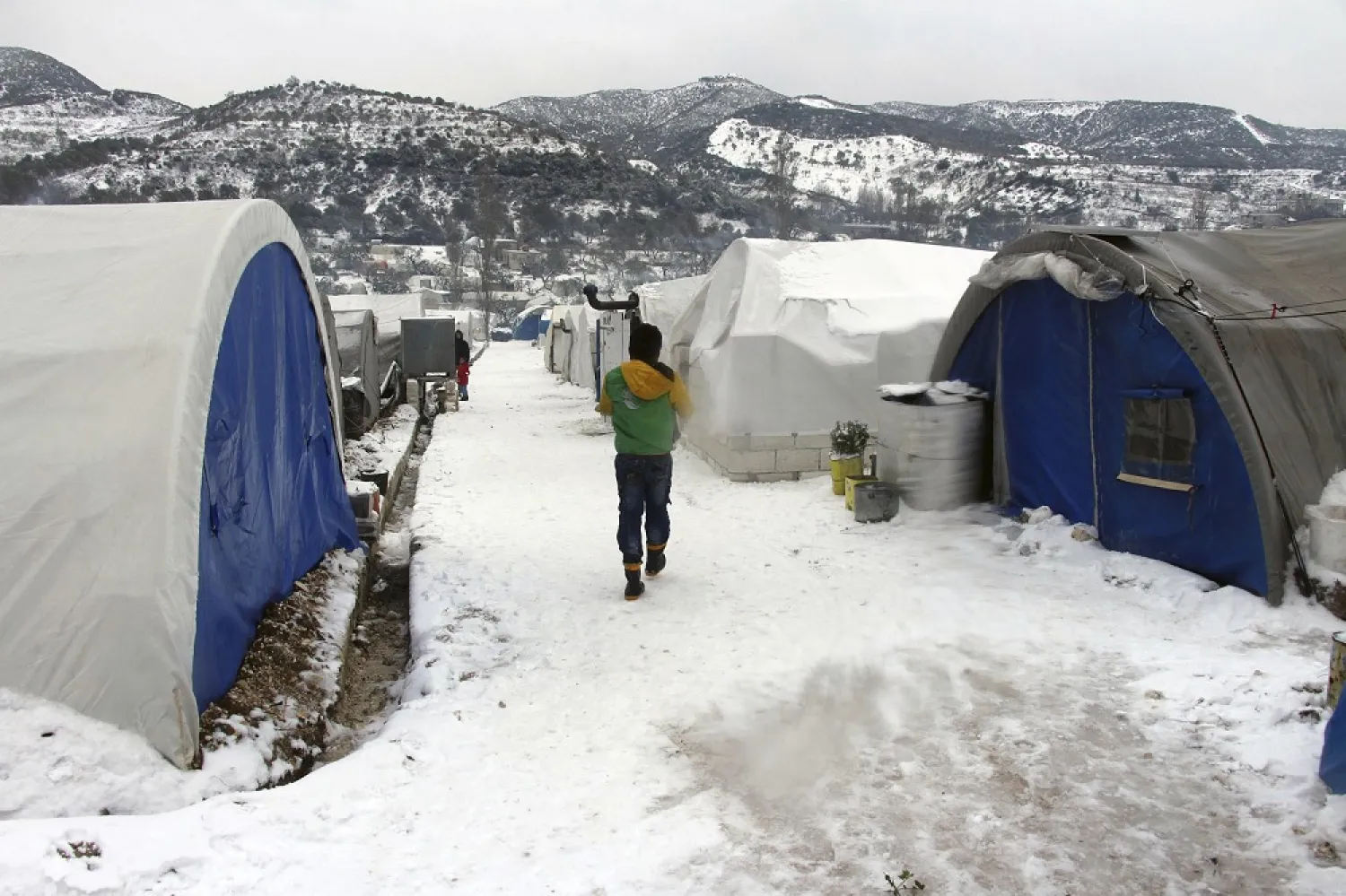 This Thursday, Feb. 13, 2020 photo released by the Syrian Civil Defense rescue group shows Syrian walking outside their tents at a displaced people camp near Turkish border, in Idlib, Syria. (AP)