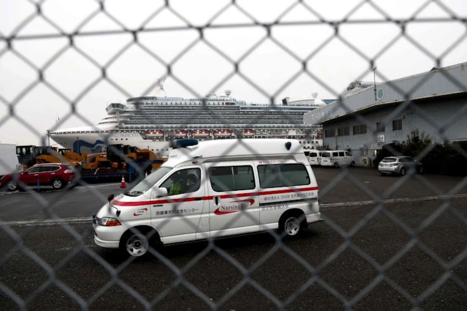 سيارة إسعاف تغادر رصيف ميناء يوكوهاما الياباني حيث ترسو السفينة السياحية الخاضعة للحجر الصحي (أ.ف.ب)