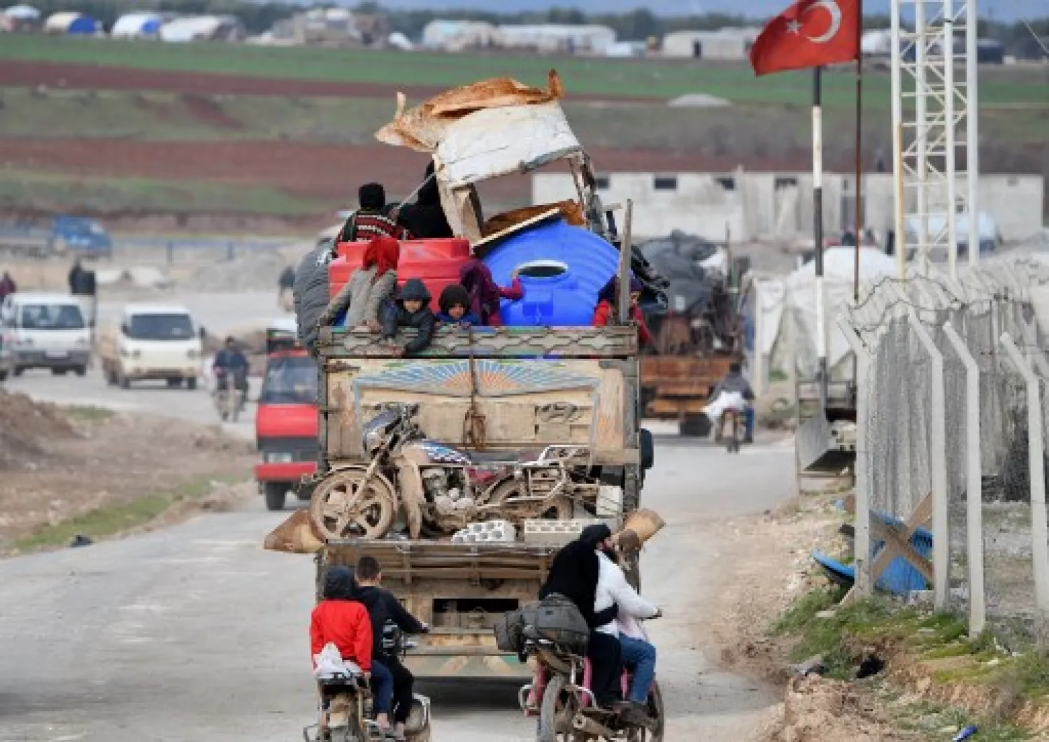 Vehicles carrying internally-displaced persons (IDPs) and their belongings drive past the IDP camp by Dayr Ballut near the Turkish border in the west of the northern Syrian province of Aleppo on February 16, 2020, as people flee advancing government forces in Idlib and Aleppo provinces. (Rami al SAYED / AFP)