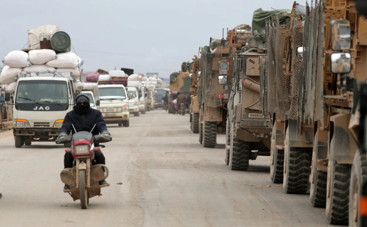 A man rides on a motorbike past Turkish military vehicles in Hazano near Idlib, Syria, on Feb. 11, 2020. (Reuters)